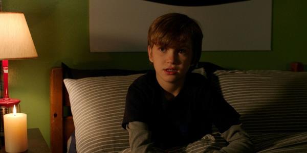 Martin sitting on his bed and looking scared in Lights Out