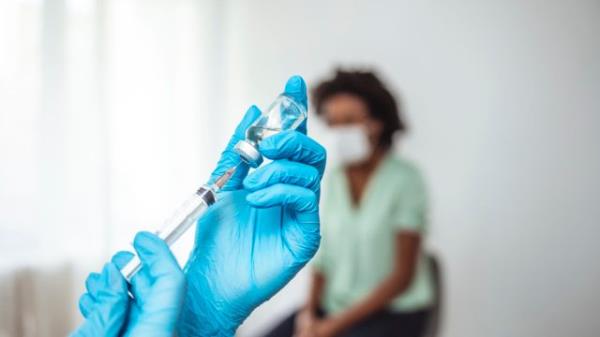 Doctor's hands in surgical gloves preparing COVID-19 vaccine for female patient. Female doctor pulling COVID-19 vaccine liquid out from vial with syringe. Prevention and immunization from corona virus infection