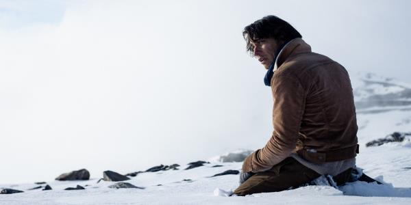 Enzo Vogrincic kneeling in the snow in Society of the Snow