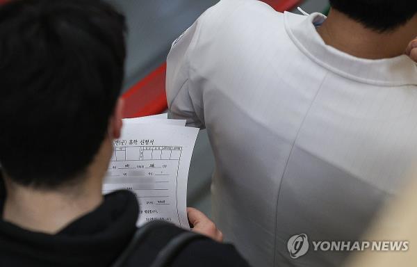 A medical school student holds application forms for a leave of absence from school at a general hospital in the southern city of Daegu on Feb. 20, 2024. (Yonhap)