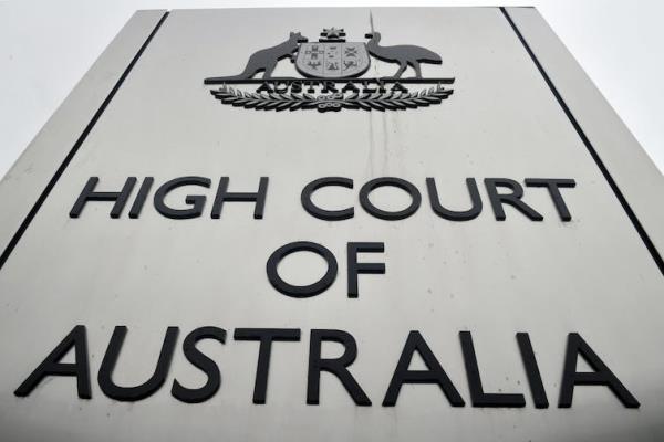 A from-below close-up of the silver sign reading 'High Court of Australia'.