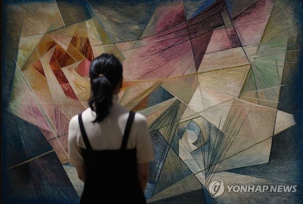 A woman examines an embroidered artwork featured in the exhibition, 