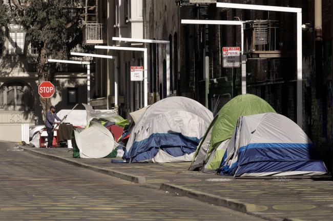 A person stands next to tents on a sidewalk in San Francisco on April 21, 2020. Photo by Jeff Chiu, AP Photo